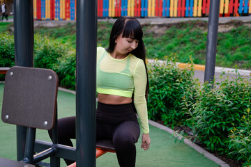 sporty woman in black and green sportswear doing sport exercises outside on sport playground. perfect healthy slim body.