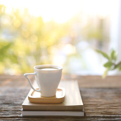 Green tea in white cup with books and plant pot on wooden table