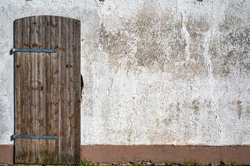 Bröckelnder Putz und gepflegte Holztür an einem alten Schuppen