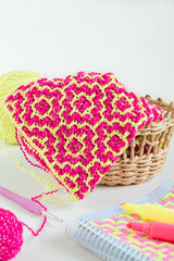 Bright crochet fabric with pink yellow rhombus. Modern knittted texture with ethnic geometric pattern. Modern needlework concept.