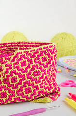The process of creating a shopping bag with a bright ethnic geometric pattern. Pink yellow crochted...