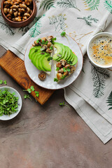 Open toasts with baked mini champignons, avocado slices, radish microgreens and cream cheese. Light healthy lunch in a plate on a board with a tablecloth. Minimalistic table setting.