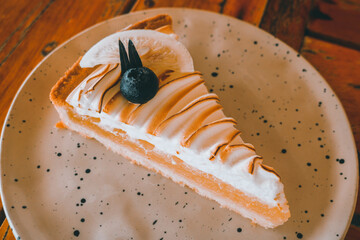 Lemon meringue pie topped with blueberry on white plate. Dessert concept.