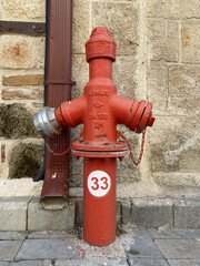 Fototapeta na wymiar red fire hydrant near vintage stone wall in Antalya old city. Antalya province in Turkey