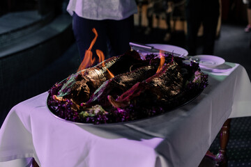 a large piece of fried meat on fire at the cook in the restaurant