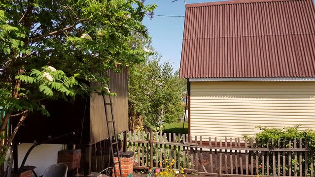 Modern rural authentic house with siding and outbuildings in the backyard, the concept of summer life in the countryside, 4k video.