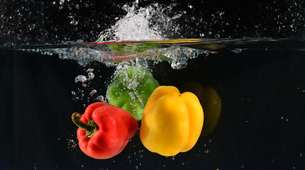 Close up of The red, yellow and green bell peppers fell into the water and the water splashed up...