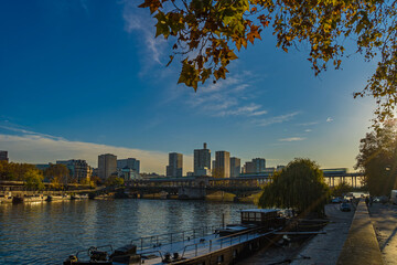 Fototapeta premium Wide View of Bir Hakeim Bridge in Paris Under Sun With Fall Colors Trees Seine River and Boats