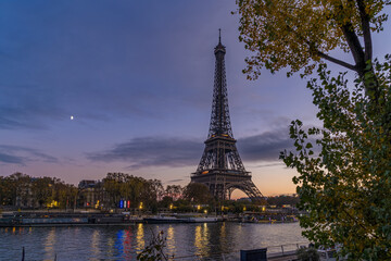 Fototapeta premium Purple Sky in Paris at Twilight Sunset Over Eiffel Tower With Moon and Trees