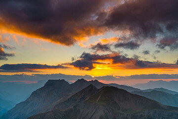Obraz na płótnie Canvas Colorful and Epic Cloudy Sunset Over French Alps Mountains Peaks in the Shadow of Sun