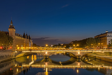 Fototapeta na wymiar Dusk in Paris With Blue Sky and Enlighened Bridges and Buildings With Reflections On Seine River
