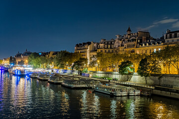 Obraz premium Night Traffic at Paris Seine River With Boats Docks and Buildings