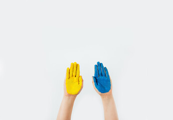 children's hands painted in blue and yellow are raised up on a white background with free space for text