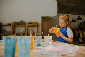Creative child sitting with paints at the table