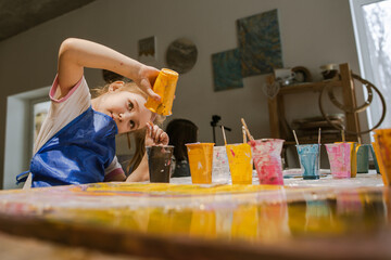 Child girl mixing paints in art studio