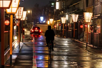 Poster Eenzame fietser en taxi op met lantaarns omzoomde weg door Kyoto na regen © Osaze