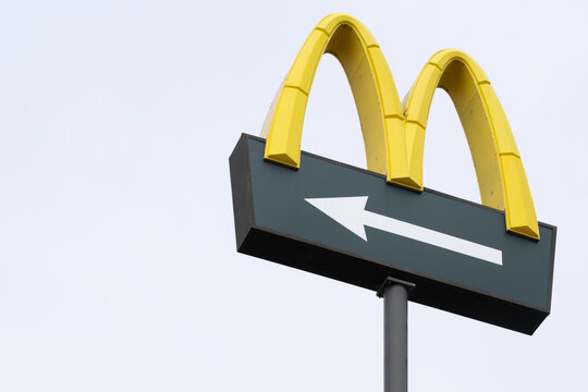 LEMMER, NETHERLANDS - MARCH 29, 2022: McDonalds logo on light background. White arrow shows road users the way. McDonald's Corporation is the world's largest chain of hamburger fast food restaurants