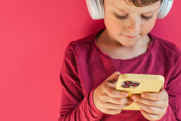 Boy in wireless headphones using smartphone in studio