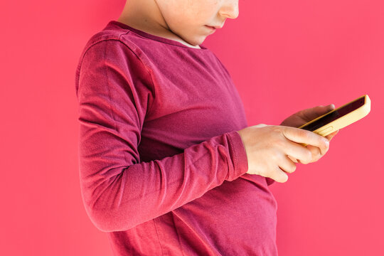 Anonymous kid using smartphone in pink studio