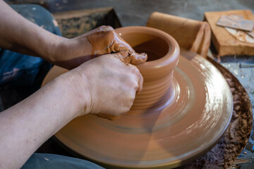 hands of a potter, creating an earthen jar on the circle