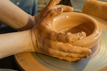 Potters hands are creating earthenware on potters wheel. Concept of natural materials, hand made and creativity
