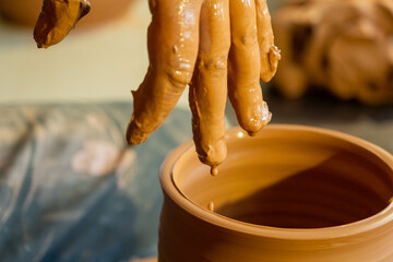 Hands of potter making a clay jug closeup
