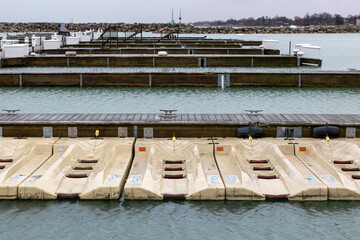 Marina with empty boat slips. Jet ski slips also empty. Cleat hitches along the pier. Wooden...
