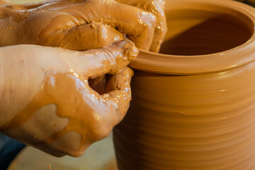 hands of a potter, creating an earthen jar on the circle