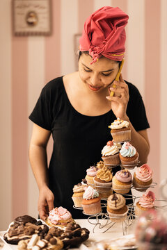 Hispanic female baker speaking on smartphone