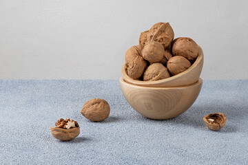Walnuts in a wooden bowl. Textured background, horizontal orientation.