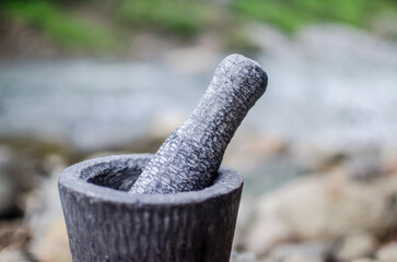 used granite mortar and pestle with fire place as a background. traditional primitive grinder made with stone. best for primitive and traditional background.