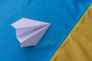 paper airplane on the background of the flag of Ukraine