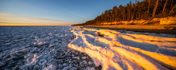 Snow and ice in sunset light on Baltic sea shore. Winter nature. - obrazy, fototapety, plakaty