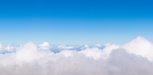Blue sky above white clouds, background image for concepts of climate, weather, flight, dream, peace with negative space for copy