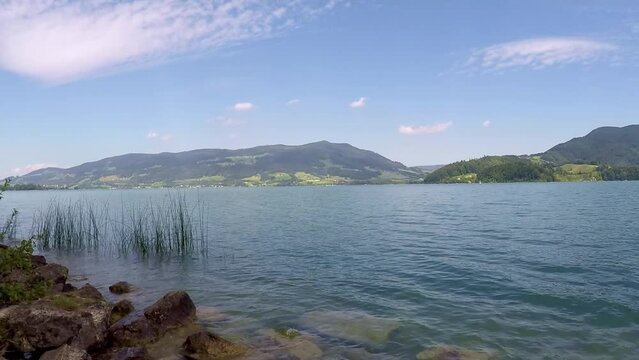 beautiful lake in austria named mondsee with mountains, waving reeds and wavy water a sunny day with a blue sky all in all a georgous summer day