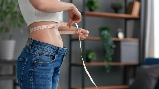 Unrecognizable woman body oversize jeans dieting results abdominal muscle waist size measurement