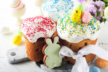 Traditional Easter sweet bread or cakes with white icing and sugar decor and quail eggs over white wooden table. Various Spring Easter cakes. Happy Easter day. Christian traditions. Top view.