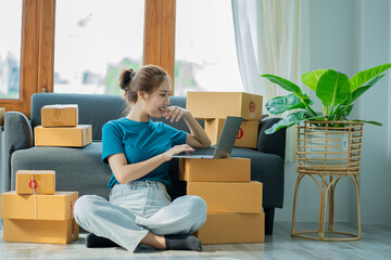 Asian woman working with box and laptop at home at work Starting a small business owner Entrepreneurship, small business, SME or freelance online and delivery ideas.