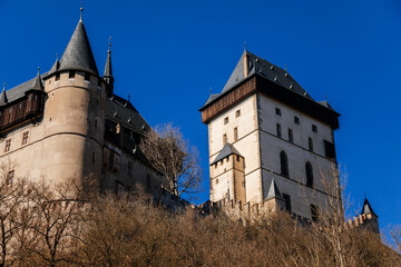 Obraz premium Karlstejn, Bohemia, Czech Republic, 12 March 2022: old royal medieval gothic castle with tower founded by king Charles IV, blue sky at sunny spring day, famous landmark, battlements fortified walls
