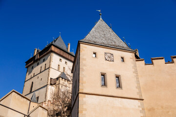 Fototapeta na wymiar Karlstejn, Bohemia, Czech Republic, 12 March 2022: old royal medieval gothic castle with tower founded by king Charles IV, blue sky at sunny spring day, famous landmark, battlements fortified walls