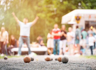 Friends playing petanque guy celebrate victory above summer cafe outdoor activity sunset light	
