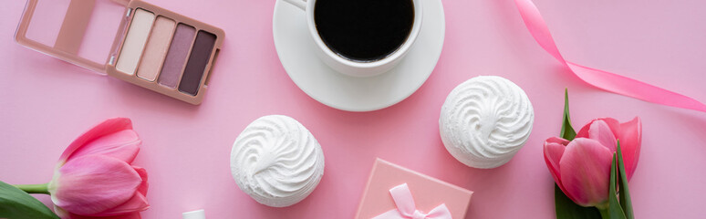 top view of zephyr, eye shadow palette and tulips near cup of coffee on pink, banner.
