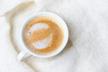 Cup of coffee in bed with blanket seen from above