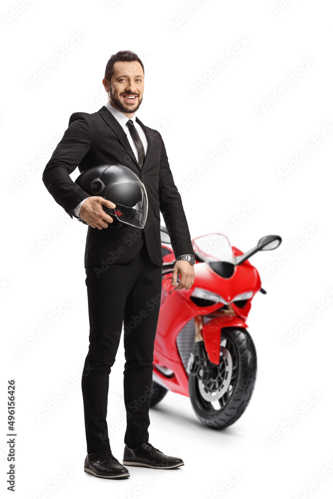 Poster full length portrait of a businessman holding a helmet and posing with a red motorbike