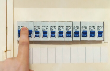 Male hand switching on fuse board.