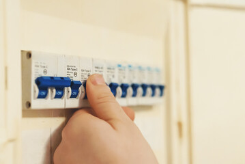 Male hand switching on fuse board.