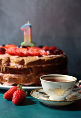 Still life with cake and cup of black tea. Strawberry layer cake close up photo. Beautiful retro styled tableware on a table. Birthday celebration photo.  