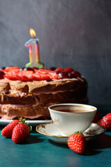 First Birthday's cake on a table. Close up photo of strawberry cake, fresh juicy berries and cup of tea. Beautiful homemade dessert photo.  