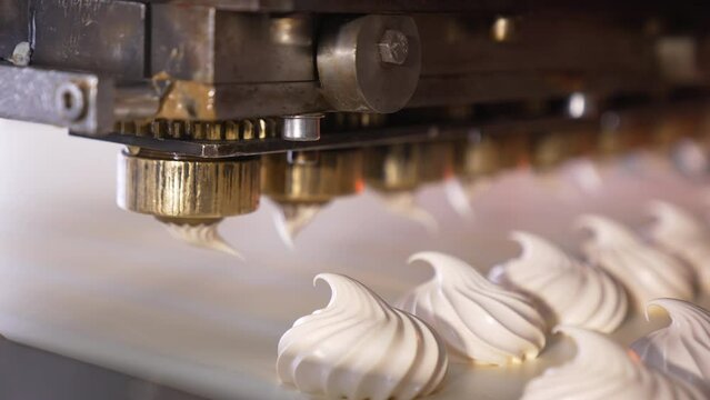 Spinning nozzles of an automatic machine produce marshmallows. Sweet desserts production at confectionary. Close up.