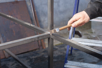 a man with a hammer beats scales when welding on an iron structure